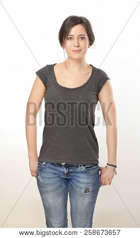 Nice Brunette Woman In T-shirt And Jeans Keeping Hands In Her Pockets