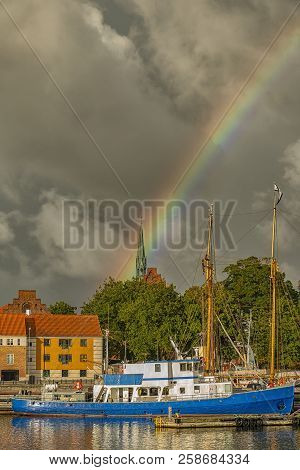 A Rainbow Rises Over A Docked Ship In Helsingor, Denmark.
