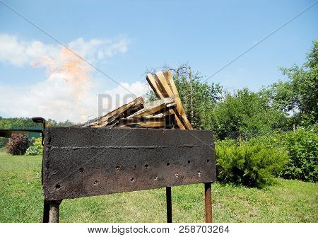 Beautiful Red Fire From Slice Wood, Dark Grey Black Coals Inside Metal Brazier. Wood Burning In The 