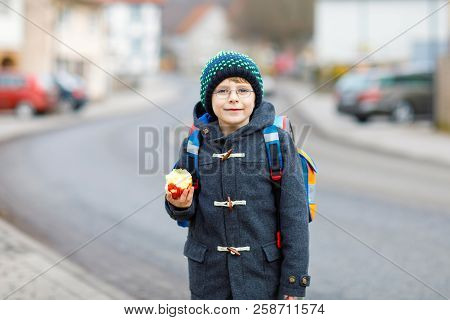 Little Kid Boy With Eye Glasses Walking From The School And Eating Apple