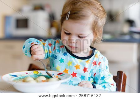 Adorable Baby Girl Eating From Spoon Vegetable Noodle Soup. Food, Child, Feeding And People Concept