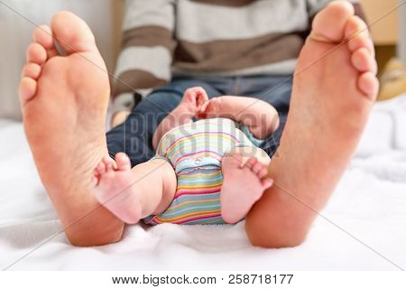 Closeup Of Huge Feet Of Father And Little Newborn Baby