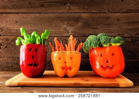 Healthy Halloween Food. Vegetables For Dipping In Jack O Lantern Bell Peppers. Side View Against Rus