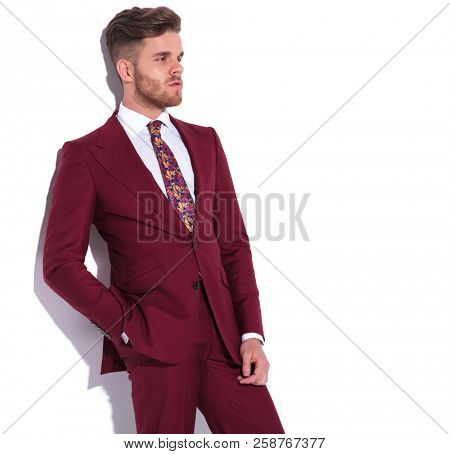 relaxed modern elegant man with hands in pocket looks away to side on white background