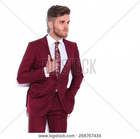elegant young businessman holding collar and looking away to side on white background