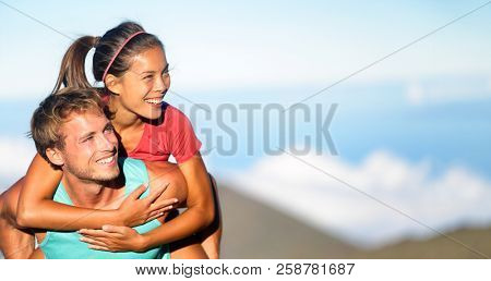 Happy young couple piggybacking outside. Fitness woman and man in love smiling excited having fun together outdoors in nature looking to side at copy space. Mutiethnic couple, Asian and Caucasian.