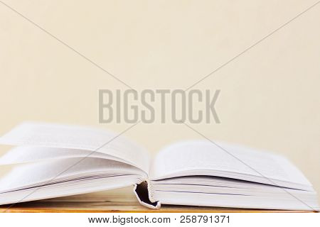 Opened Book Lying On Wooden Table Blank White Wall Background. College School University Education L