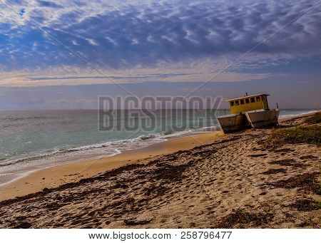 An Abandoned Catamaran Vessel On A Florida Beach As The Sky Begins To Darken Overhead