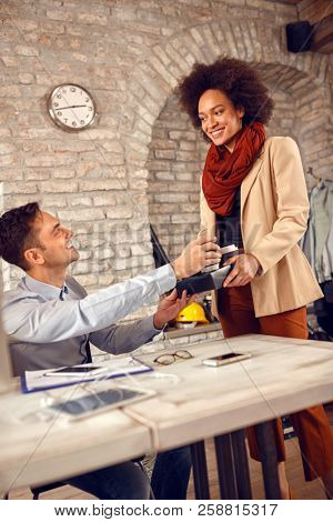 Woman serves coffee in office to young male employee 