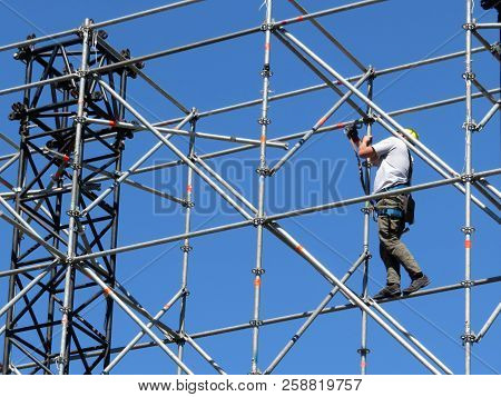 Construction Worker Working On Scaffolding. Steeplejack On The Background Of Clear Blue Sky