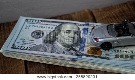 A Stack Of One Hundred Dollar Bils On Wooden Background