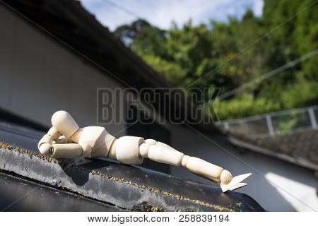 Wooden Doll Sleeping Face Up On A Asian Roof Tiles In Front Of Green Forest