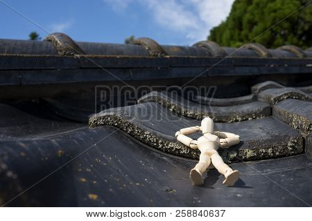 Wooden Doll Sleeping Face Up On A Asian Roof Tiles Under Blue Sky