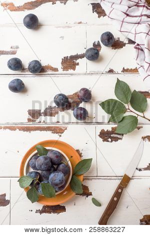 Fresh Plum Berries On A Plate With Leaves On A Light Table.