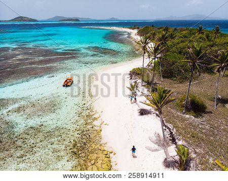 Aerial drone view of Petit Tabac tropical island, turquoise Caribbean sea of Tobago cays, and a family with kids in St Vincent and Grenadines