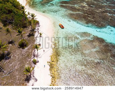 Aerial drone view of Petit Tabac tropical island, turquoise Caribbean sea of Tobago cays, and a family with kids in St Vincent and Grenadines