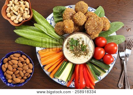Colorful Vegetables, Lettuce, Falafels  And Humus On A Plate On A Wooden Background.