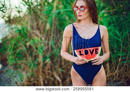 Beautiful Young Female In Swimsuit And Red Sunglassses Hold Slice Of Watermelon With Inscription Lov