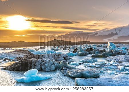 Sunset At The Iceberg Lagoon In Iceland, Snow Cape Mountains In The Background, Cloudy Sky