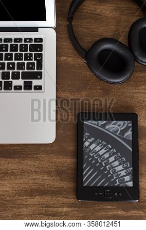 Laptop On The Table With Wireless Headsets And Ebook