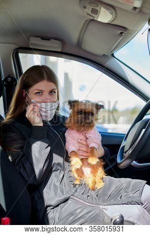 Girl In White Medical Gauze Mask In The Car With A Dog In Sunny Spring Day. Protection Against Disea