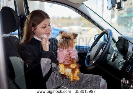 Girl In White Medical Gauze Mask In The Car With A Dog In Sunny Spring Day. Protection Against Disea