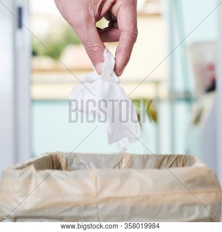 closeup of a young caucasian man indoors about to throw a used wet wipe to the trash bin