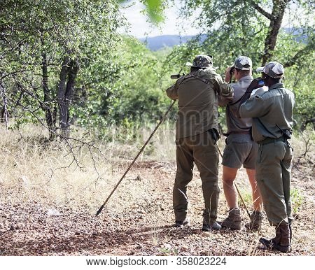 Hunter, Huntsman And Tracker Before Shooting On The Hunt. Three Men During A Trophy Hunt In Africa. 
