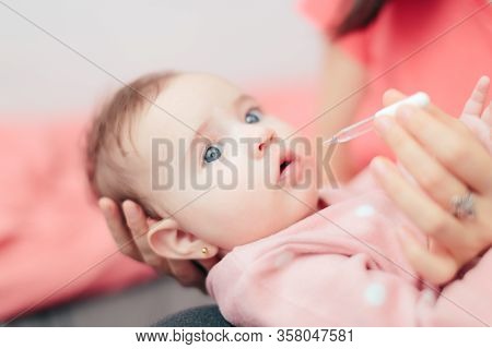 Mother Administrating Vitamin D Medicine To Her Baby