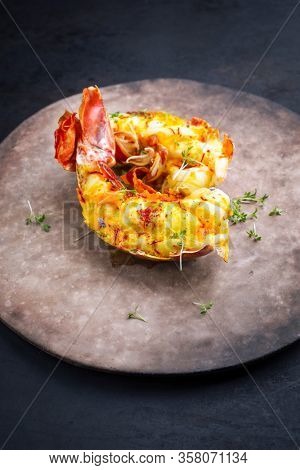 Traditional barbecue spiny lobster tail sliced and offered with saffron lemon sauce as closeup on a rustic modern design plate with copy space 