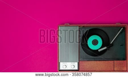 Old Vinyl Player And Turnable On A Fuchsia Background. Entertainment 70s. Listen To Music. Top View.