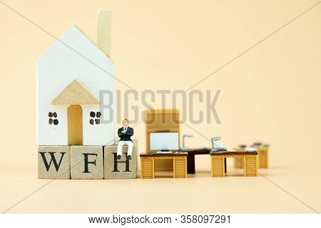 Miniature People: Businessman Sit On Wood Blocks Of Wfh With Wooden Home And Miniature Office Table 