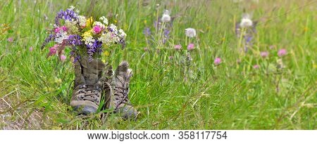 Bouquet Of Wilf Flowers In Hiking Shoes On A Flowered Meadow