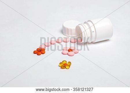 White plastic bottle with medicines and vitamines. tematic health. rose, yellow and red medicines.