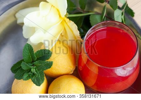 Red Orange Juice O Grapefruit Juice In A Glass On Steel Plate With Mint Leaf, Lemons And Yellow Rose