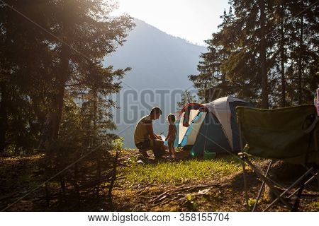 A Little Girl With Her Father Near A Tent In Nature In A Mountain Fir Forest. The Father And Daughte