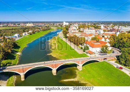 Panoramic View Of Town Of Sisak In Croatia From Drone, The Old Town Center And Bridge Over Kupa Rive