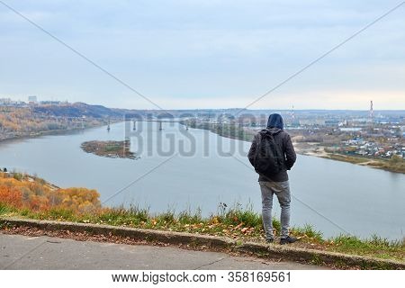 Young Guy On Top Of Hill Looking At River And Cityscape, Back View. Self-reflection Of Young Man, Th