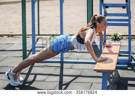 Sporty Young Sexy Woman Doing Push-ups From Bench On Sports Ground. Concept Healthy Lifestyle