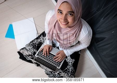 Muslim female student with laptop in classroom