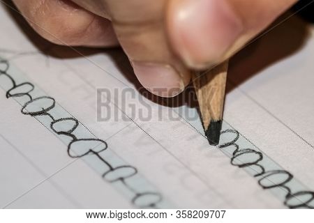 Close Up Of Primary School Kid Doing Homework On Letter Write Excercise Book