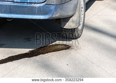 Drops Of Gasoline Flow On Asphalt From A Parked Car. Environmental Pollution By Combustible Motor Fu