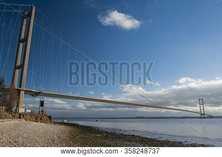 Large Suspension Bridge Spanning A Wide River Estuary On A Clear Day With Blue Sky And Clouds