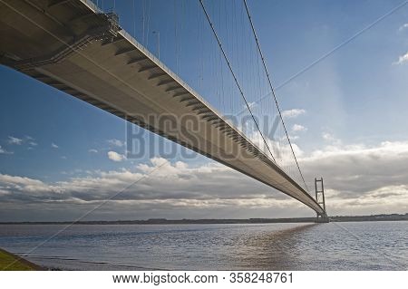 Large Suspension Bridge Spanning A Wide River Estuary On A Clear Day With Blue Sky And Clouds