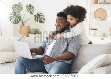 Family Conference. Black Father And Little Daughter Using Laptop At Home, Making Video Call To Grand