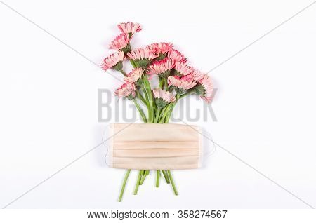 Quarantine Concept. Face Medical Mask On Pink Herbera Flowers. Flat Lay