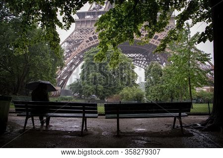 A Woman Sitting On The Bench Waiting For The Rain