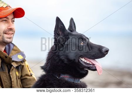 German Black Shepherd With Its Owner On The Sandy Beatch Of Black Sea