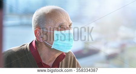Man In Protective Face Mask Anti Virus Looks At City Street Through Window