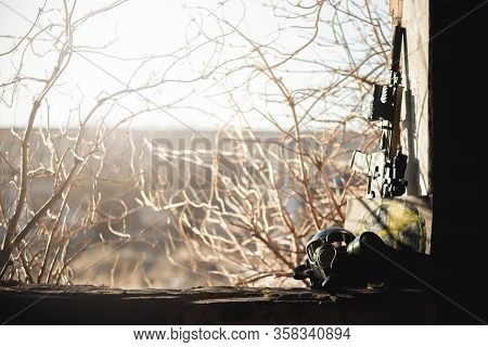 Gas Mask, Rifle And Radiation Sign On The Abandoned Building Window Background. Post Apocalypse.